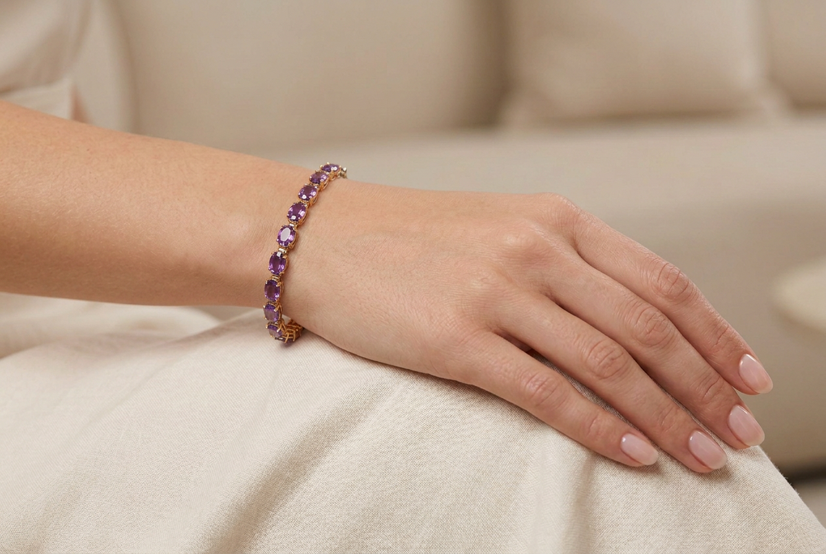 A yellow gold tennis bracelet featuring a row of round-cut purple amethyst gemstones, displayed horizontally on a clean white background.